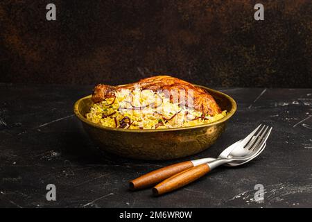 Indian dish Biryani chicken with basmati rice in metal brass old bowl on table Stock Photo