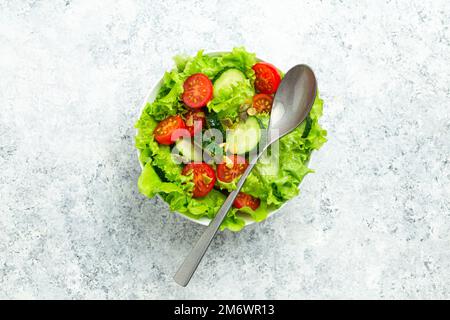 Healthy tomatoes cucumber iceberg leaves salad on white table top view Stock Photo