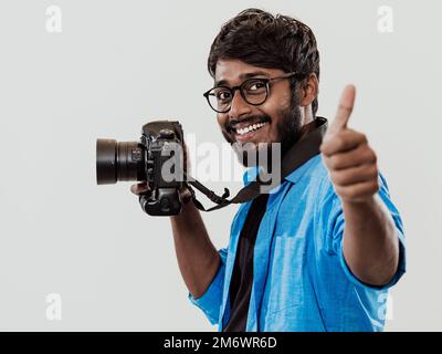 Professional photographer having DSLR camera taking picture.Indian man photography enthusiast taking photo while standing on blu Stock Photo