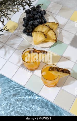 Two pineapple cocktail on edge of swimming pool. Summer vacation and travel concept. Exotic summer drinks. Stock Photo