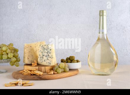 Wine bottle of white wine with blue cheese and grapes on light background. White wine with cheese and fruits. Wine bottle mockup Stock Photo