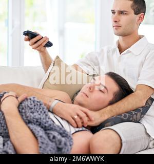Taking it easy today. a young gay couple relaxing on a sofa at home. Stock Photo