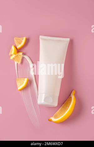 White mock up bottle for branding with lemon slices. Cosmetics concept with fruit acids. Cosmetic mock up on pink background. Stock Photo
