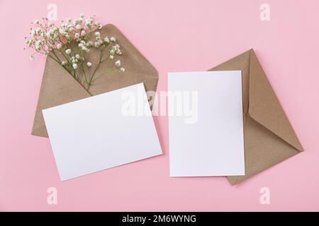Blank greeting cards and envelopes with gypsophila on pink background. Blank paper sheet cards with mockup copy space. Minimal w Stock Photo