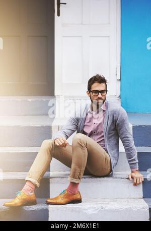 Hes a man of style. Full length shot of a stylish man sitting on a step outside. Stock Photo