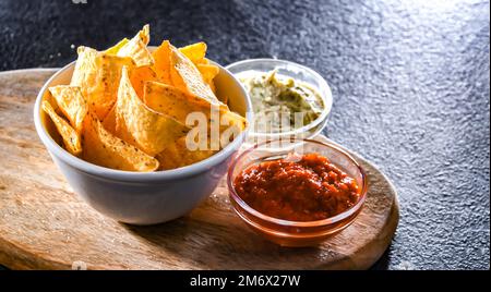 Composition with a bowl of tortilla chips and dipping sauces Stock Photo