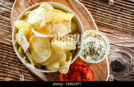 Composition with a bowl of potato chips and dipping sauces Stock Photo