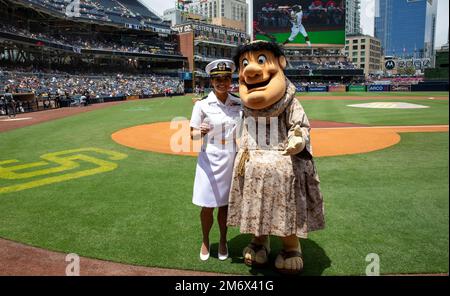 SAN DIEGO (May 8, 2022) – LT j.g. Lael Sommer poses for a photo with the San Diego Padre’s mascot the swinging friar on the field at Petco Park, May 8. The swinging friar has been the mascot of the San Diego Padres as early as 1958. Stock Photo