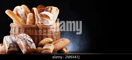 Wicker basket with assorted bakery products including loafs of bread and rolls Stock Photo