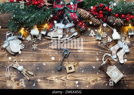 House key with keychain cottage on a festive eco friendly, natural background with Christmas tree. Happy New Year-red background Stock Photo
