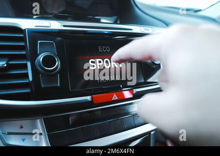 The driver is manually selecting a drive mode on a touch screen display in a car. Stock Photo