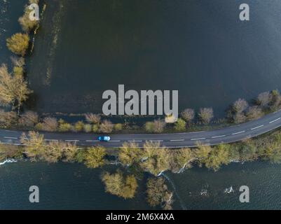 A car drives along the road as the Welney wash fills with floodwater as ...