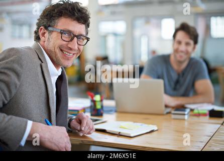 Youre looking at of the best in the biz. Portait of two people working together in a large office. Stock Photo