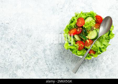 Healthy tomatoes cucumber iceberg leaves salad on white table top view Stock Photo