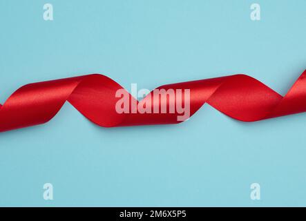 Twisted silk red ribbons for decoration on a blue background, top view Stock Photo