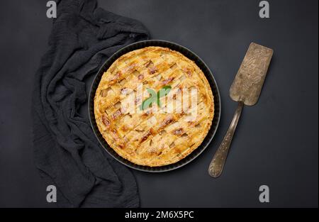 Round baked apple pie on a black table. View from above Stock Photo