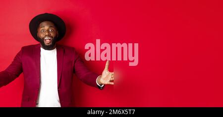 Fashion and party concept. Pleased handsome Black man spread hands in welcome gesture, reaching to receive something, looking am Stock Photo