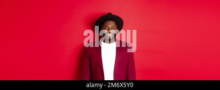 Fashion and party concept. Stylish african american man in blazer and hat, smiling confident at camera, celebrating new year, st Stock Photo