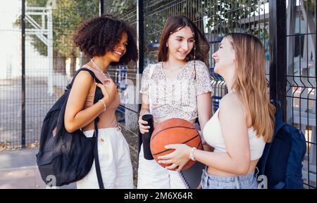 Tylish cool teen girls gathering at basketball court, friends ready for playing basketball outdoors Stock Photo