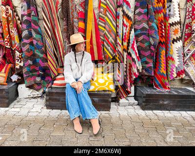 Old traditional Turkish carpet shop in cave house Cappadocia, Turkey Kapadokya. Young woman on vacation in Turkey Stock Photo