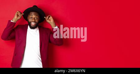 Christmas shopping and people concept. Happy Black man having fun on party, smiling happy at camera, red background Stock Photo