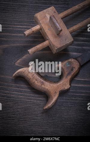 Age-old rusty hand saw wooden marking gage on wood board. Stock Photo