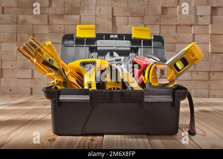 Various Work Tools In Little Black Toolbox. On Background Of Pile Wooden Beams. Stock Photo