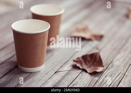 Two paper cups standing on wooden table in outdoors cafe Stock Photo