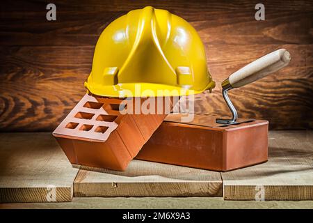 bricks trowel and helmet on vintage wood Stock Photo