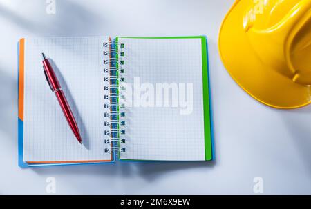 Building helmet checked notepad pen on white background. Stock Photo