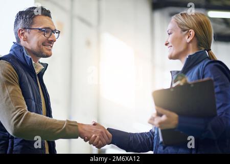 Teamwork is the order of the day. two managers shaking hands together while standing on the factory floor. Stock Photo