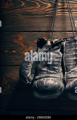 Old boxing gloves hanging on nail on wooden wall. Stock Photo