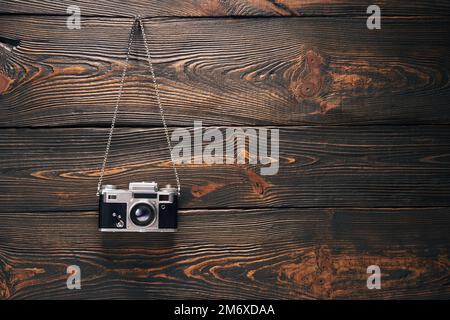 Vintage old camera hang on nail over wooden background Stock Photo