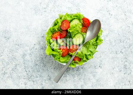 Healthy tomatoes cucumber iceberg leaves salad on white table top view Stock Photo