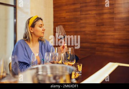 Blond woman sommelier bartender smelling white wine and making degustation card. Stock Photo