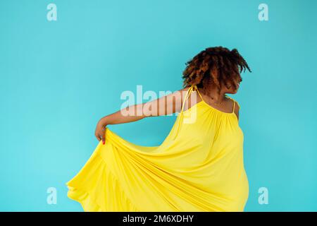 Beautiful bright joyful african woman in yellow dress in blue studio ...