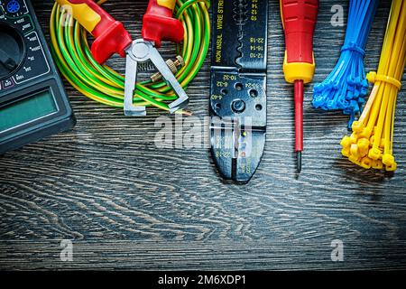 Electric tester screwdriver rolled cable ties insulation strippers on wood board. Stock Photo