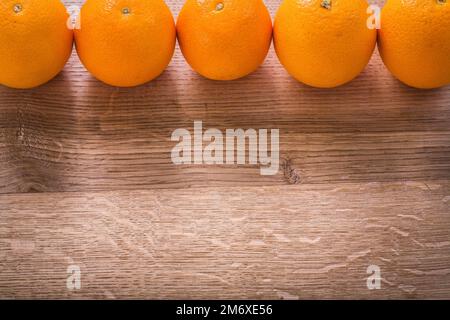 five oranges organized in row on wooden board Stock Photo