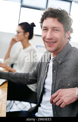 Make creativity a job. Portrait of two smiling office workers sitting at their desks. Stock Photo