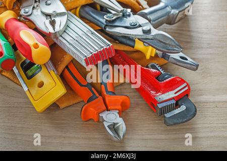 Construction tooling in leather building belt on wooden board. Stock Photo