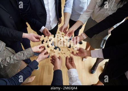 Hands man and woman in business clothes with puzzle pieces symbolize team building in office Stock Photo