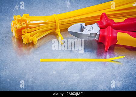 Cutting pliers yellow cable ties on metallic background construction concept. Stock Photo