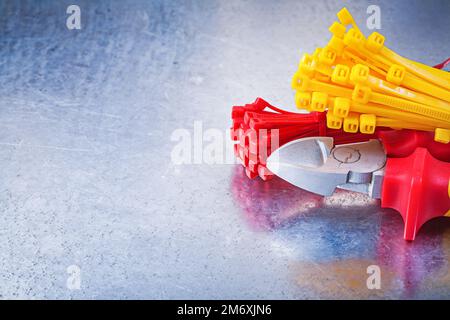 Cutting pliers plastic tying cables on scratched metallic background. Stock Photo