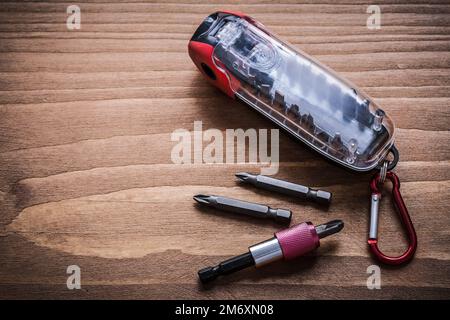 Interchangeable screwdriver heads in container on wood board horizontal version. Stock Photo