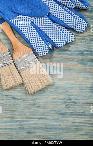 Composition of paintbrushes safety gloves on wooden board construction concept. Stock Photo