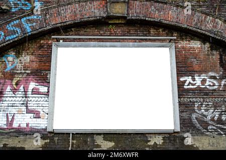 Blank billboard on dark red brick wall with graffiti in urban environment Stock Photo