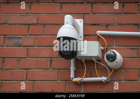 Surveillance camera system on a red brick wall, modern security technology collects video material of surrounding incidents to protect the house from Stock Photo
