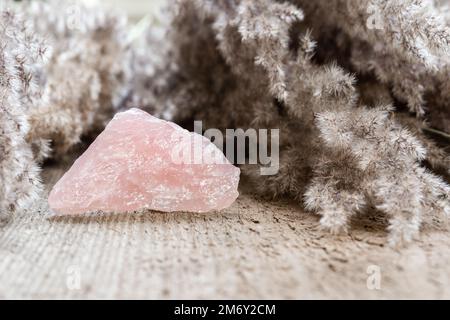 Rose quartz mineral specimen on wooden background. Rose quartz is a healing pink stone good to atract love and promote feelings Stock Photo
