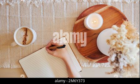 Coffee, hand and writing in journal top view with candle for calm, peace and relax morning routine. Woman, notebook and diary planning goals Stock Photo