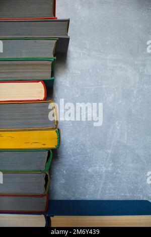 Stack of old battered books on retro photos against background concrete wall Stock Photo